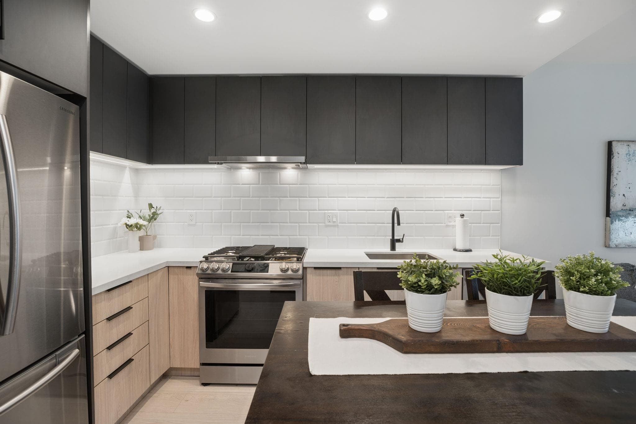 L-shaped kitchen with island, stainless appliances, and subway tile backsplash
